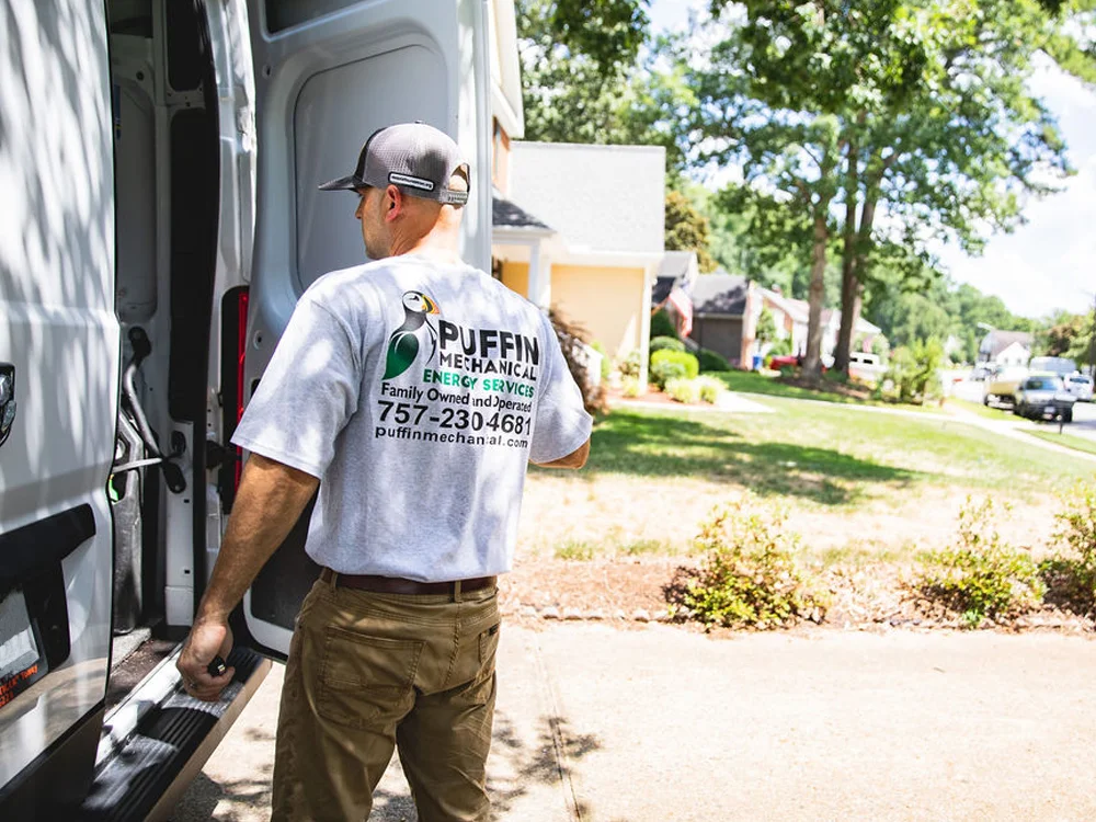 A Puffin Mechanical HVAC technician opening the door of his truck to begin repair of a heating and cooling system.