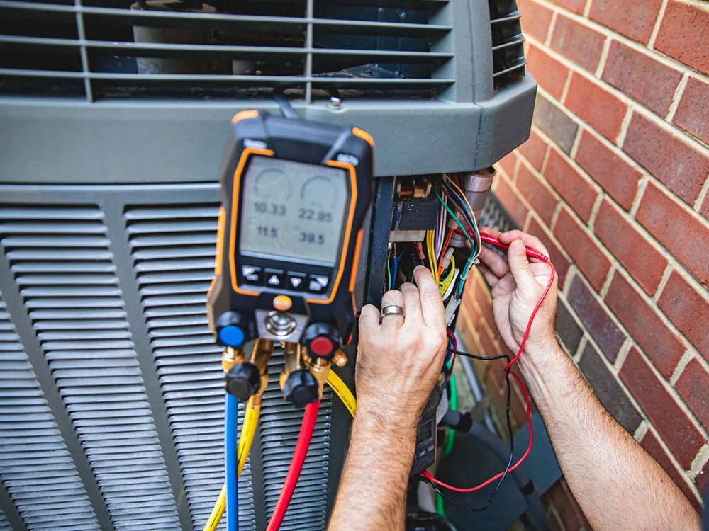 A technician running a diagnostic test on a heating and cooling compressor