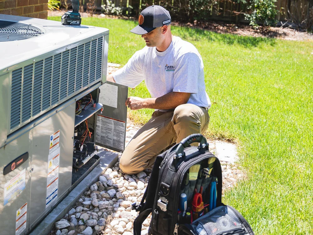 A Puffin Mechanical technician kneeling down to repair a residential HVAC system in Hampton Roads, VA